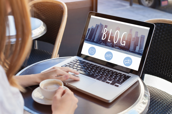 Person blogging on laptop at cafe table, SociShare, Social Media Management